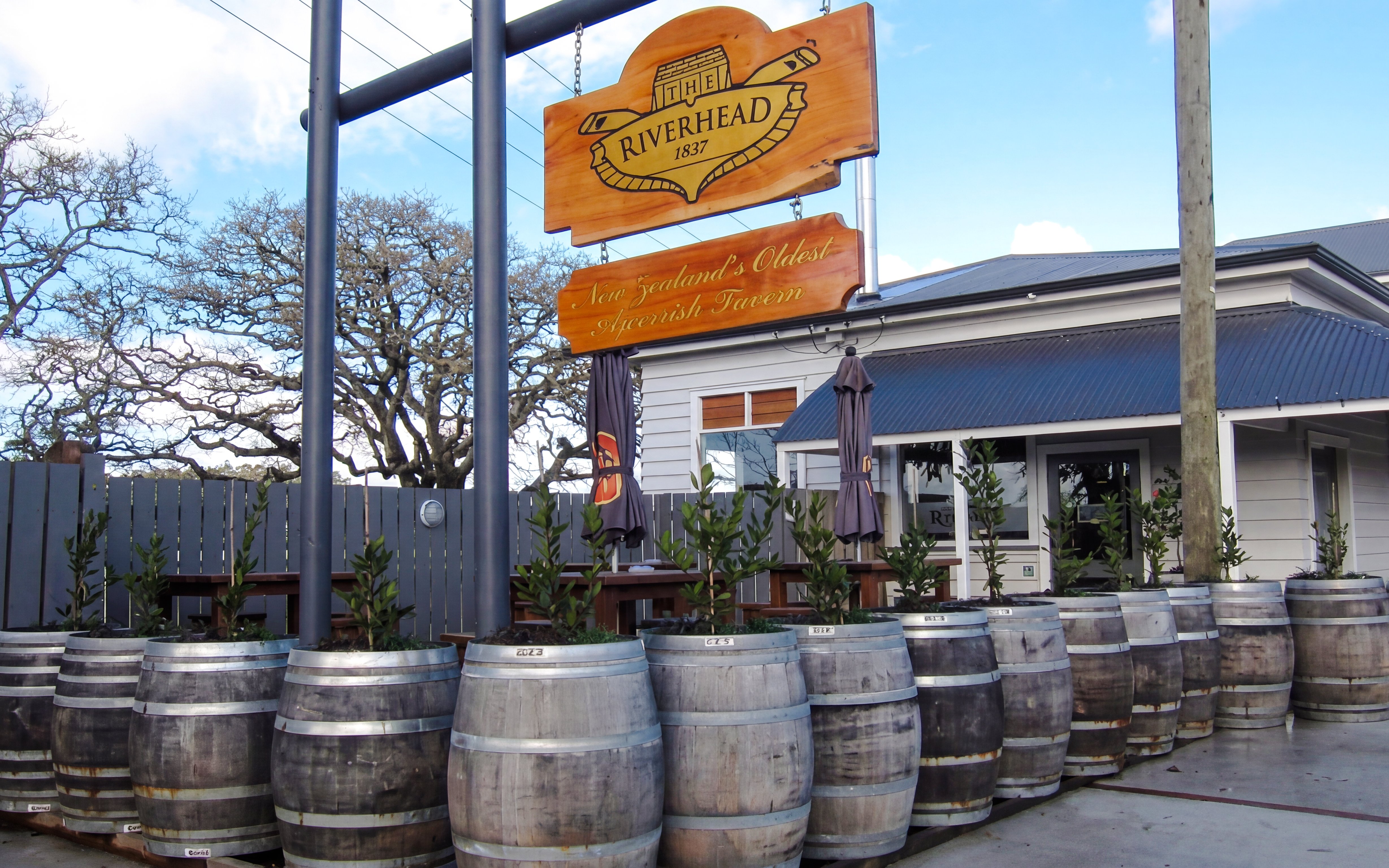 Riverhead Tavern entrance with wooden barrels and outdoor seating.