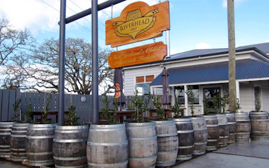 Riverhead Tavern entrance with wooden barrels and outdoor seating.