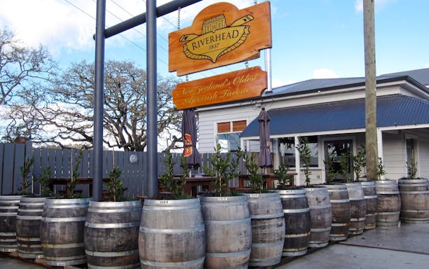 Riverhead Tavern entrance with wooden barrels and outdoor seating.