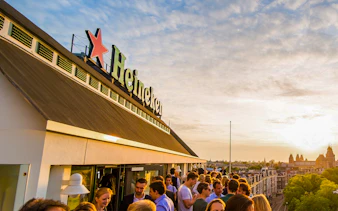 Crowd enjoying sunset at Heineken Experience rooftop in Amsterdam.
