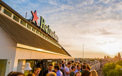 Crowd enjoying sunset at Heineken Experience rooftop in Amsterdam.