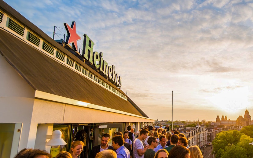 Crowd enjoying sunset at Heineken Experience rooftop in Amsterdam.