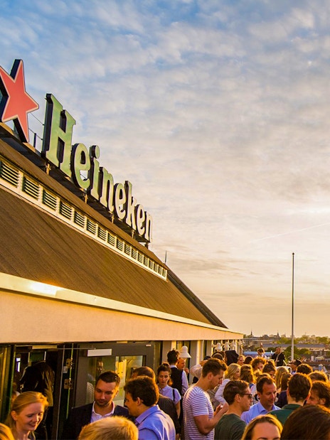 Crowd enjoying sunset at Heineken Experience rooftop in Amsterdam.
