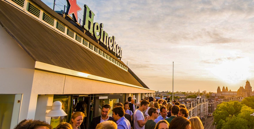 Heineken Experience tour entrance in Amsterdam with visitors exploring the brewery.