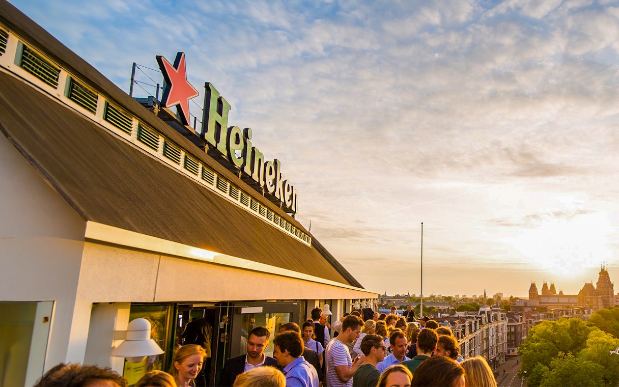 Crowd enjoying sunset at Heineken Experience rooftop in Amsterdam.