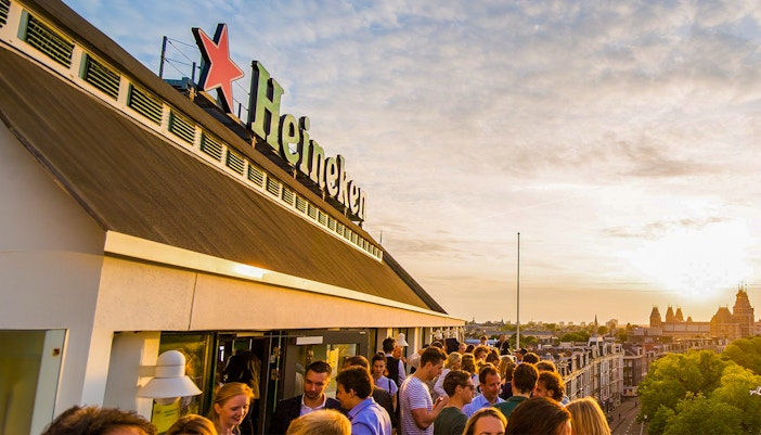 Heineken Experience tour entrance in Amsterdam with visitors exploring the brewery.