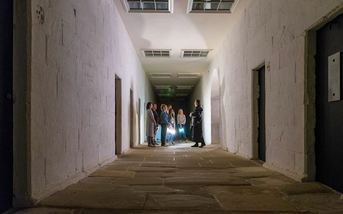 Group on a guided ghost tour in a dimly lit corridor at Port Arthur Historic Site.