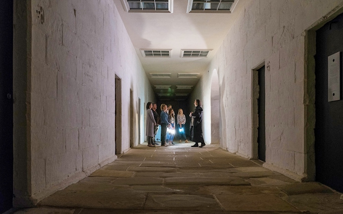 Group on a guided ghost tour in a dimly lit corridor at Port Arthur Historic Site.