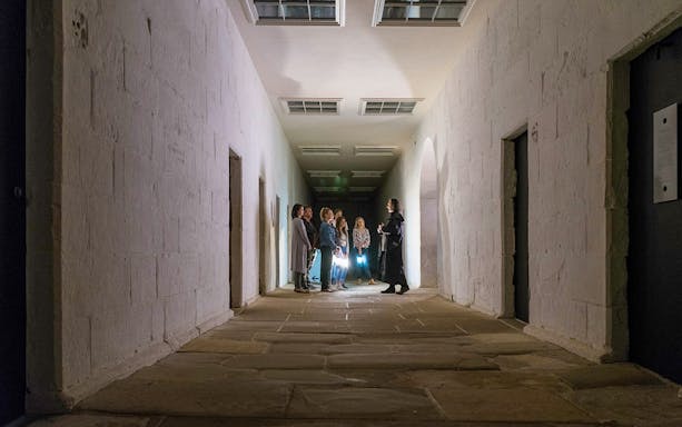 Group on a guided ghost tour in a dimly lit corridor at Port Arthur Historic Site.