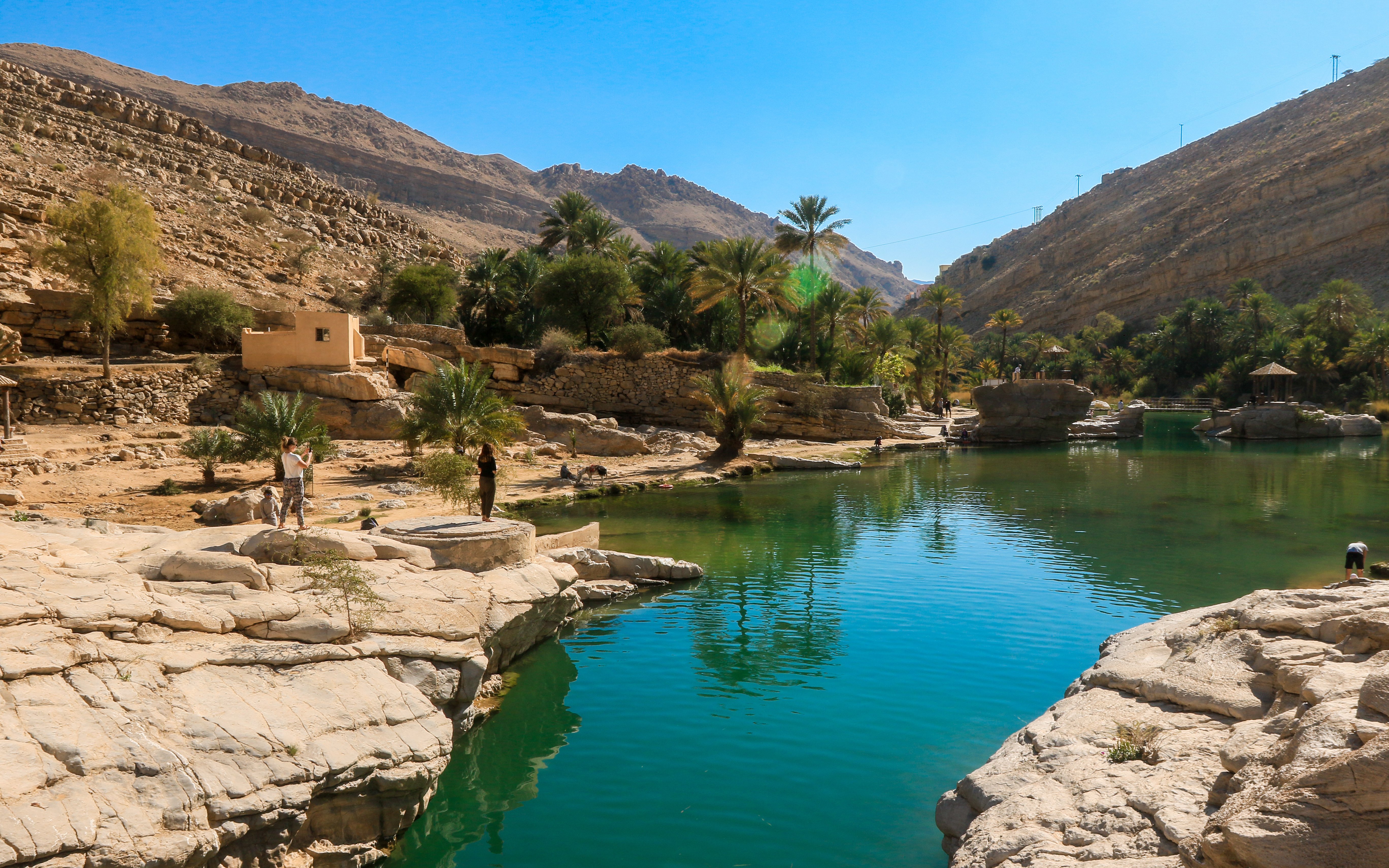 Wadi Shab Oasis in Oman with clear waters, rocky mountains, and lush greenery.