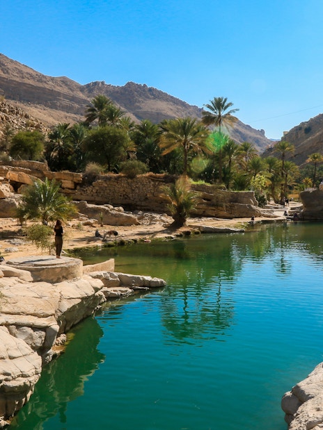 Wadi Shab Oasis in Oman with clear waters, rocky mountains, and lush greenery.