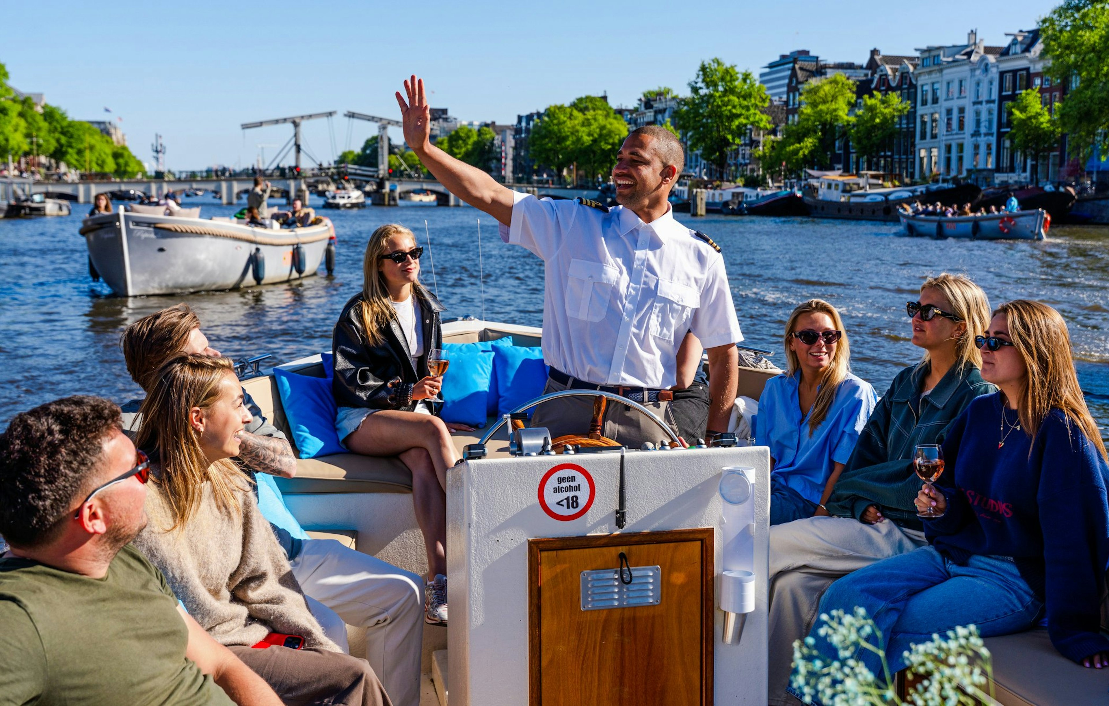Guests enjoying an open boat cruise with a guide on Amsterdam's canals.