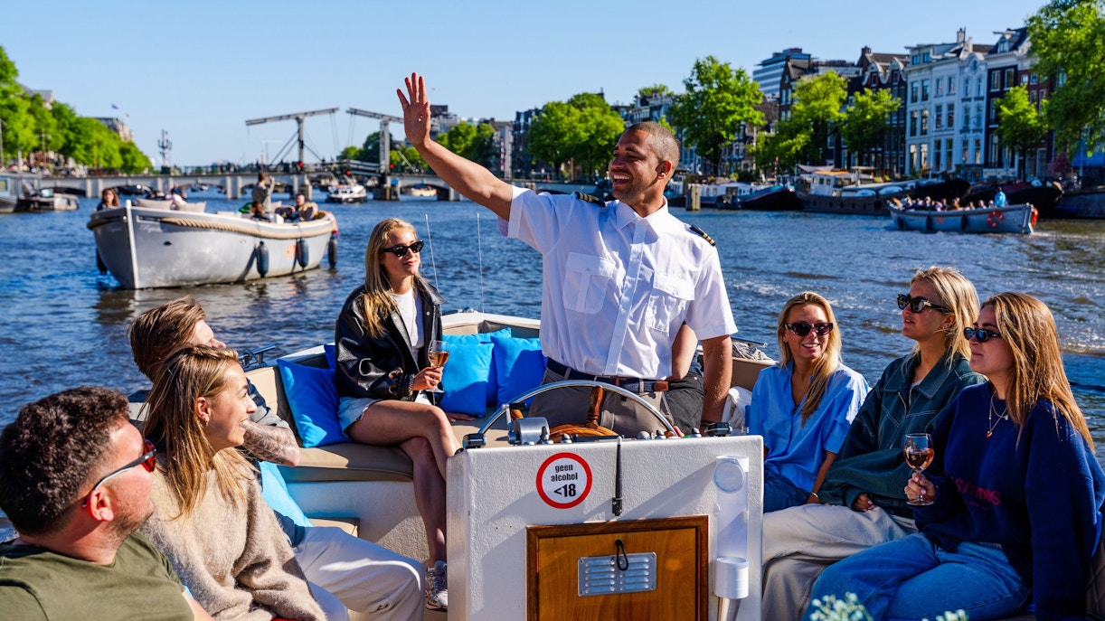 Guests enjoying an open boat cruise with a guide on Amsterdam's canals.