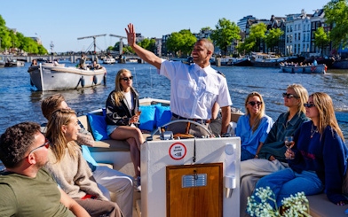 Guests enjoying an open boat cruise with a guide on Amsterdam's canals.