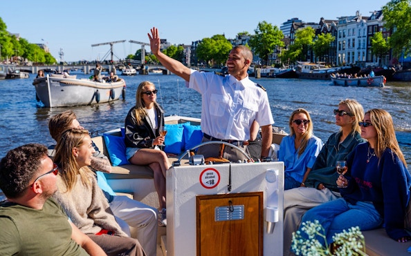 Guests enjoying an open boat cruise with a guide on Amsterdam's canals.