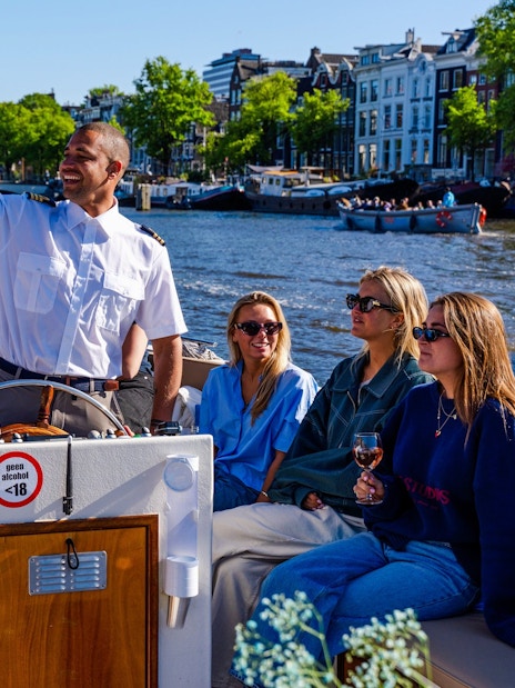 Guests enjoying an open boat cruise with a guide on Amsterdam's canals.