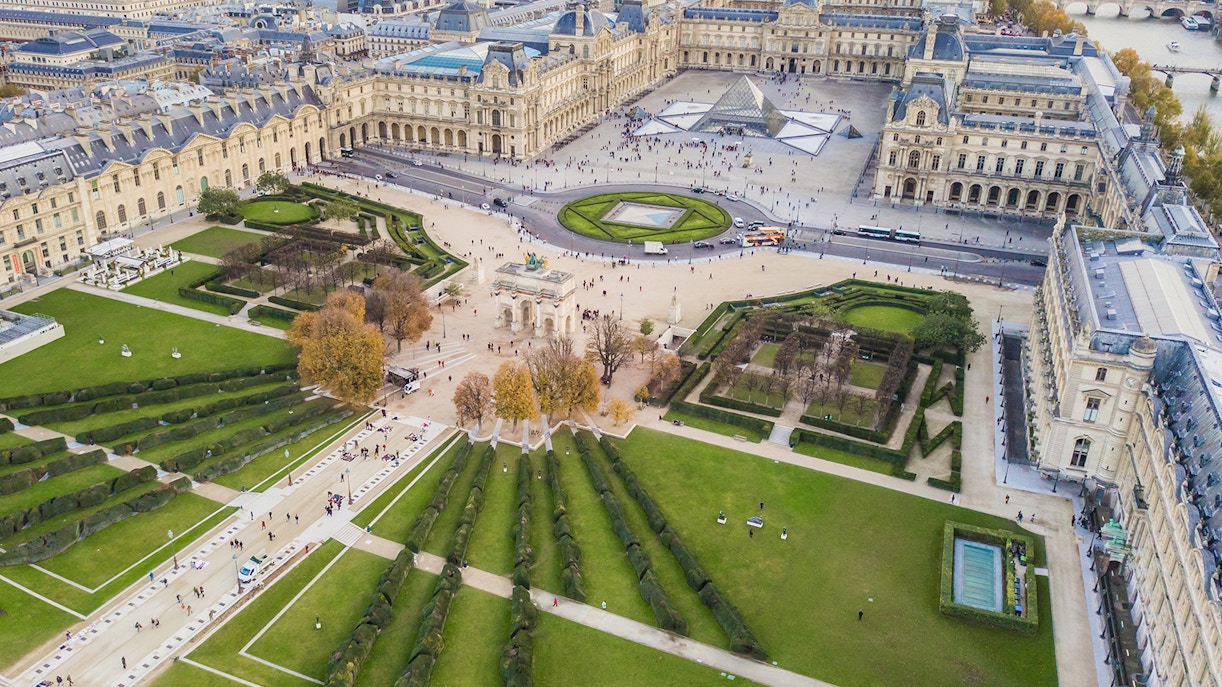 Aerial view of the Louvre Museum in Paris with the Seine River in the background.