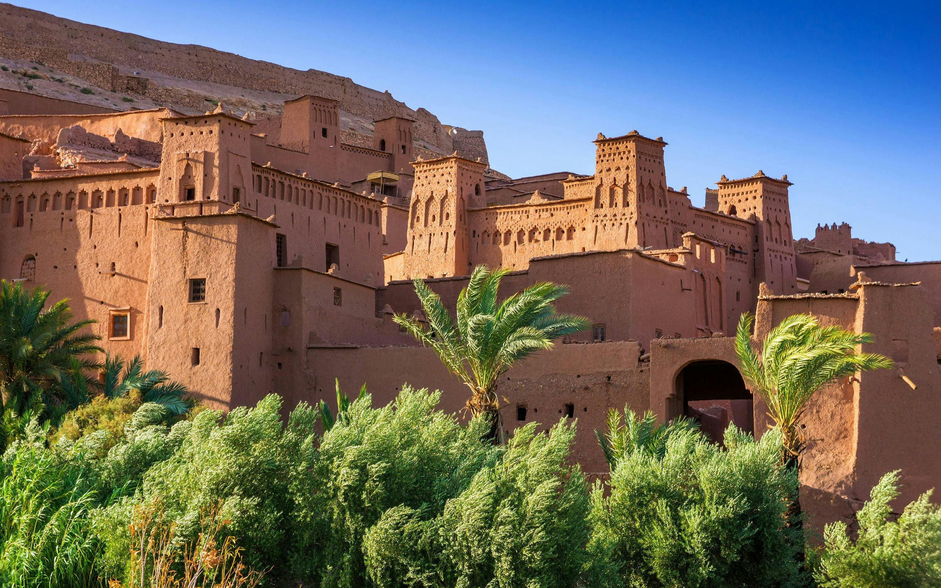 Ait Benhaddou kasbah with palm trees in Morocco.