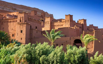 Ait Benhaddou kasbah with palm trees in Morocco.