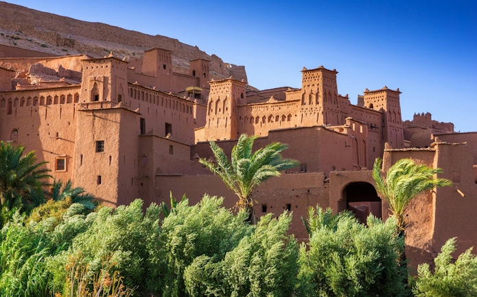Ait Benhaddou kasbah with palm trees in Morocco.