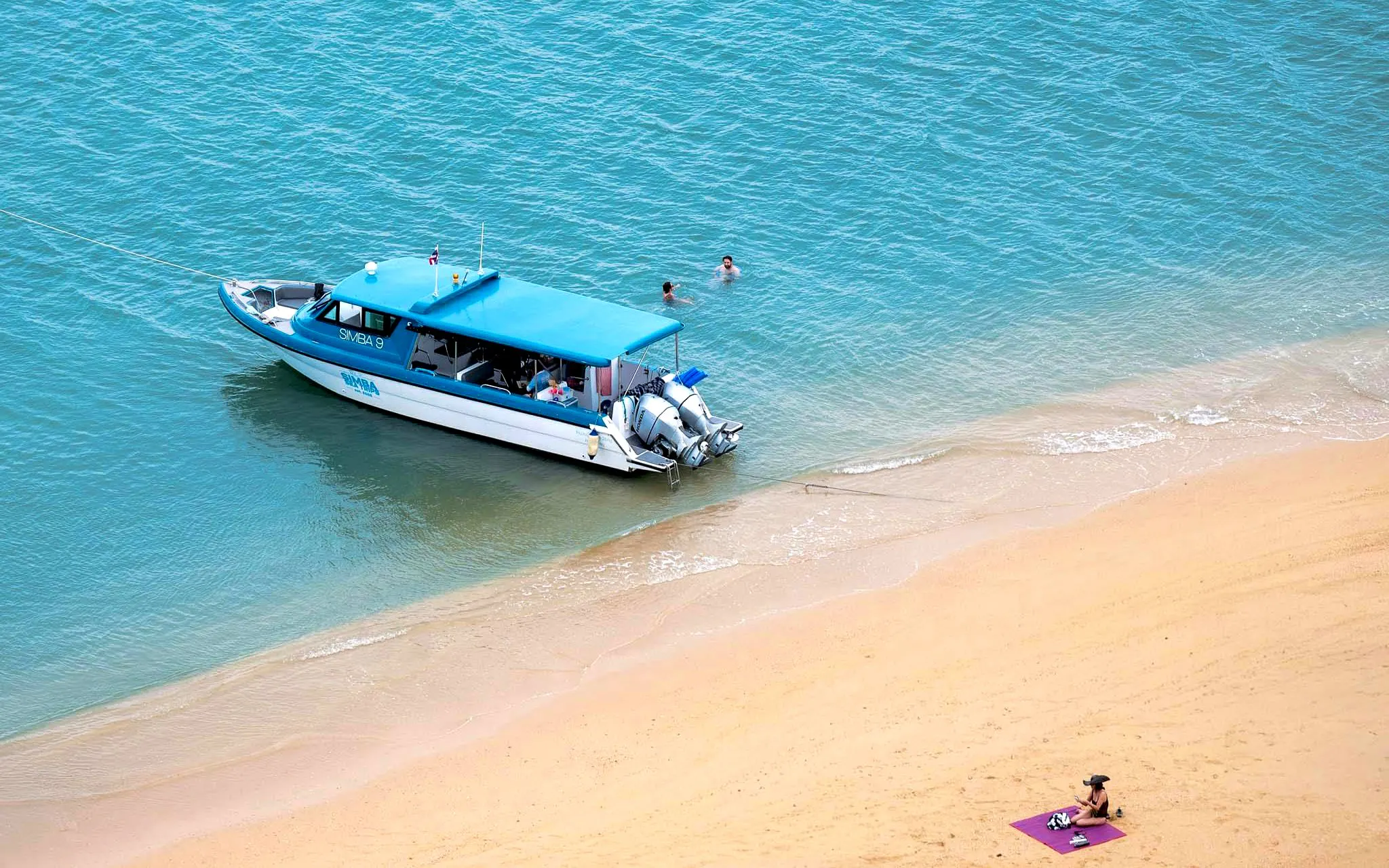 Simba 9 speedboat near tropical beach, Thailand, with swimmers in turquoise water.