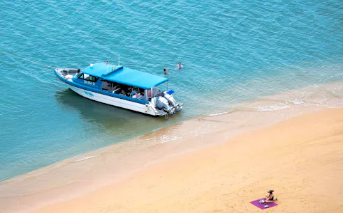 Simba 9 speedboat near tropical beach, Thailand, with swimmers in turquoise water.