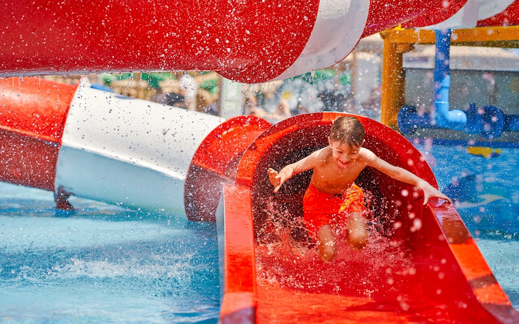 Boy sliding down a red water tube at Wet World Water Park.