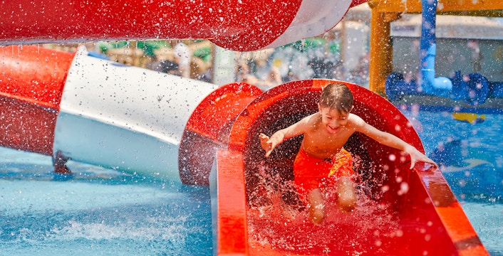 Boy sliding down a red water tube at Wet World Water Park.