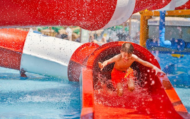 Boy sliding down a red water tube at Wet World Water Park.