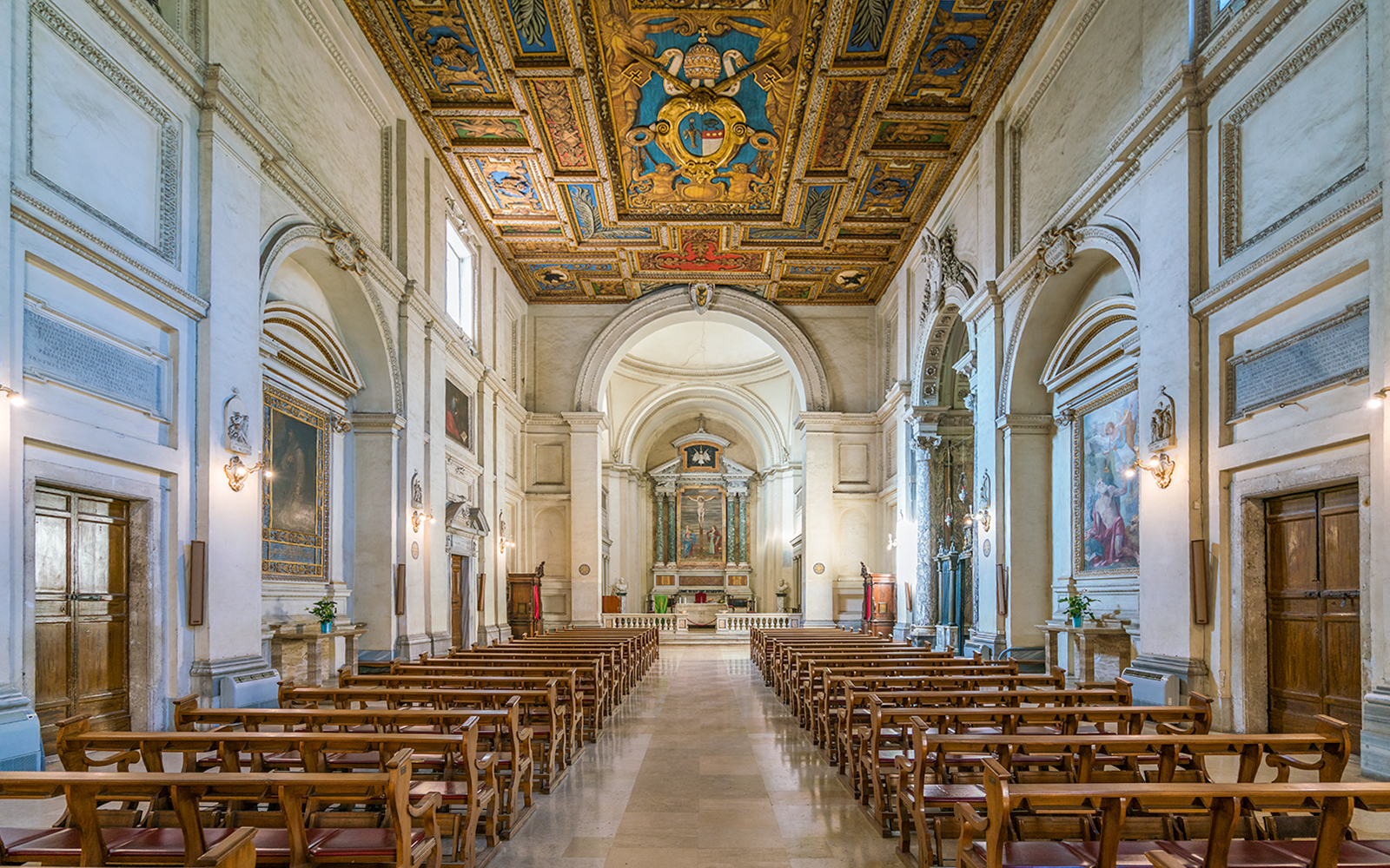 Indoor view of the Basilica of San Sebastian, featuring ornate ceiling and rows of wooden pews.