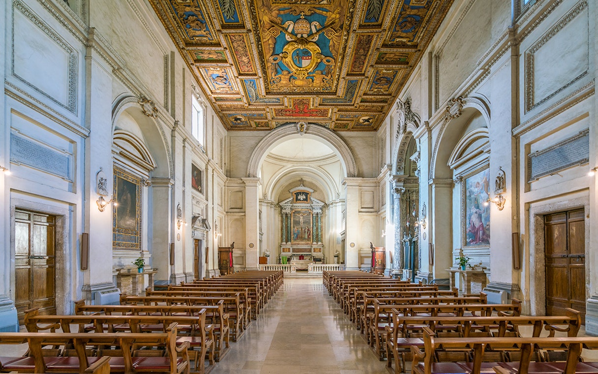 Indoor view of the Basilica of San Sebastian, featuring ornate ceiling and rows of wooden pews.