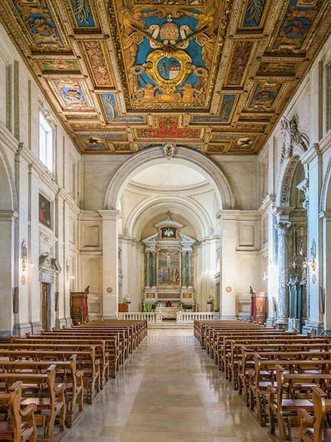 Indoor view of the Basilica of San Sebastian, featuring ornate ceiling and rows of wooden pews.