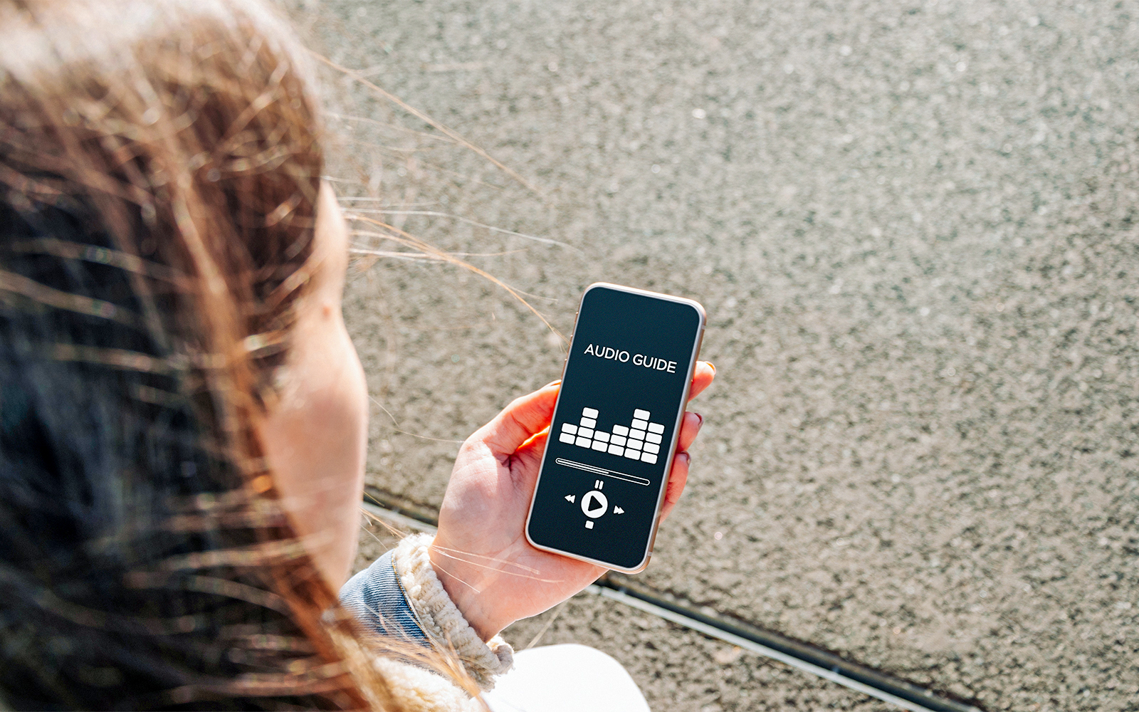 Person using an audio guide app on a smartphone at A'DAM Lookout.