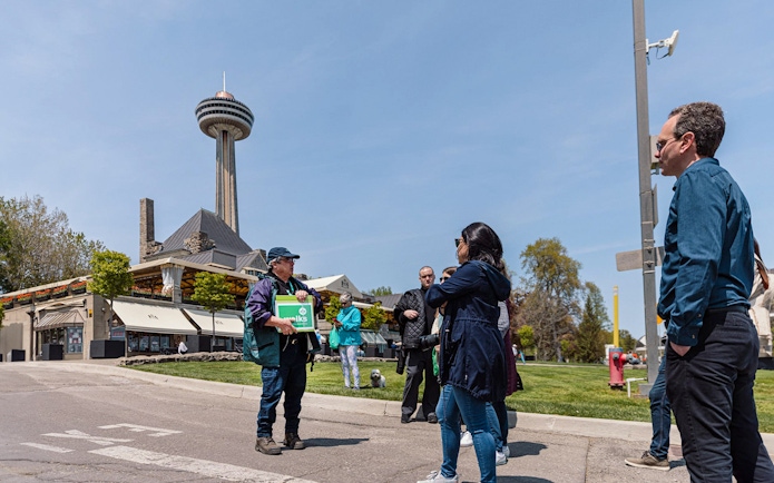 Guide welcoming tourists in front of Skylon Tower, Niagara Falls.