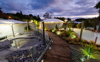 Hell's Gate geothermal mud bath area with wooden walkway and lush greenery at dusk.