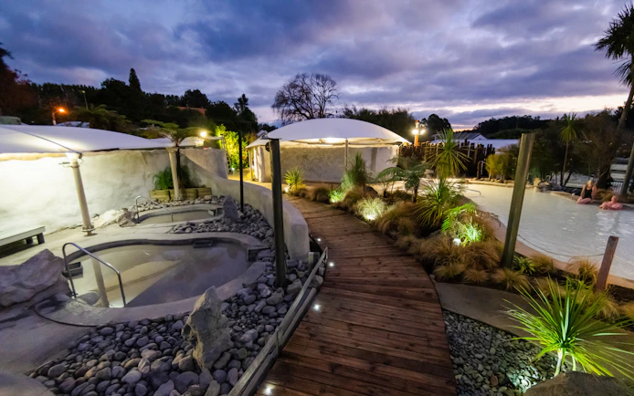 Hell's Gate geothermal mud bath area with wooden walkway and lush greenery at dusk.