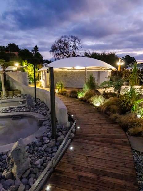 Hell's Gate geothermal mud bath area with wooden walkway and lush greenery at dusk.