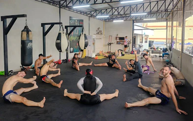 Beginners practicing stretches in a Muay Thai boxing class in Pattaya gym.
