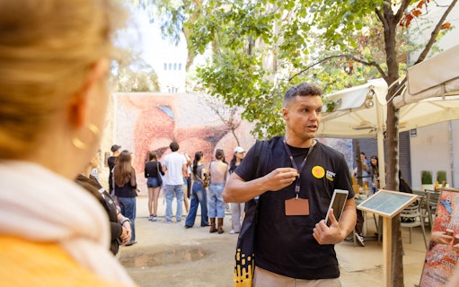 Tour guide leading a group in Barcelona near a mosaic wall.