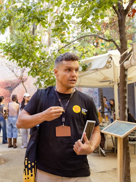 Tour guide leading a group in Barcelona near a mosaic wall.