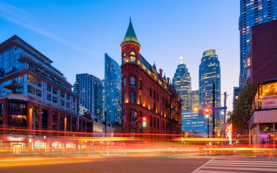 Gooderham Building with Toronto skyscrapers in the background at dusk.