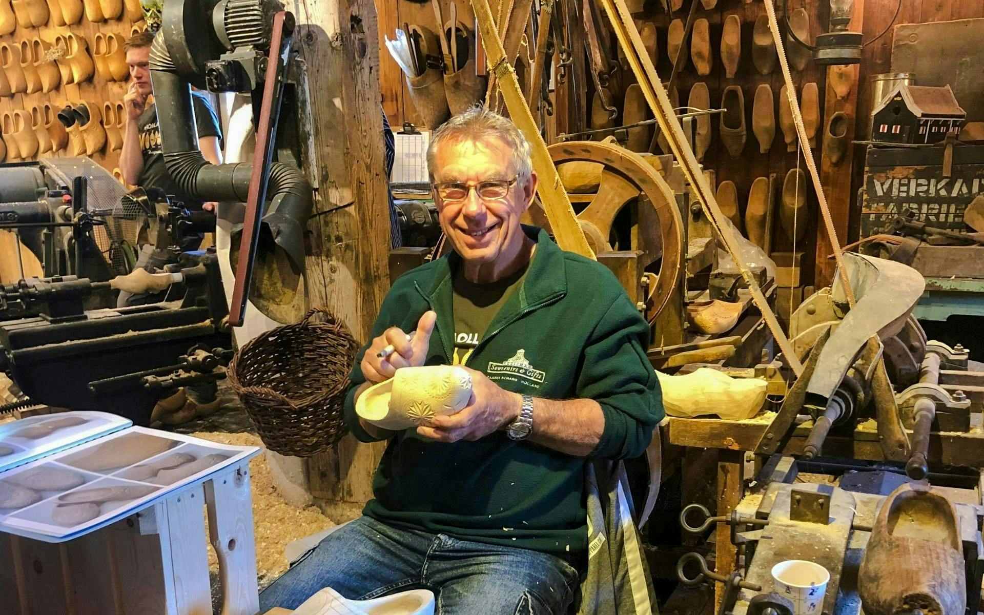 Clog maker carving wooden shoes at Zaanse Schans workshop on Volendam and Giethoorn tour.