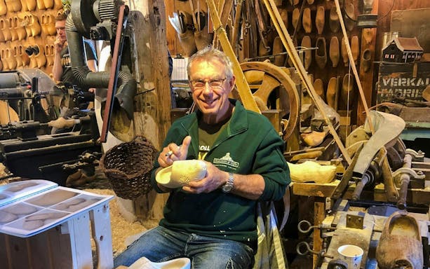 Clog maker carving wooden shoes at Zaanse Schans workshop on Volendam and Giethoorn tour.