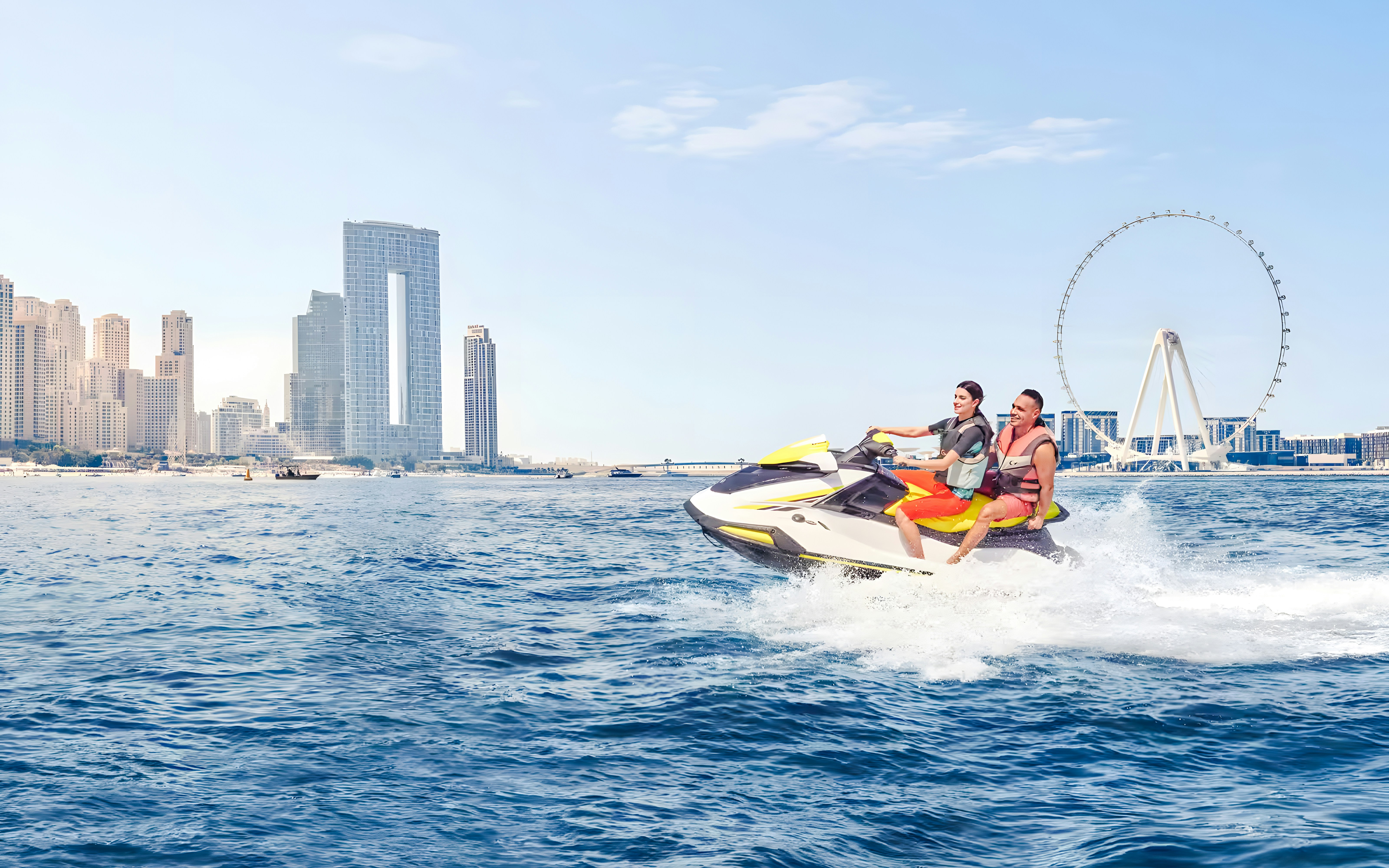 Jet ski riders near Burj Al Arab with Dubai skyline in background.
