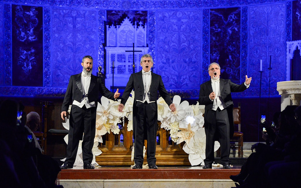 Opera singers performing on stage at a nighttime event with ornate blue backdrop.