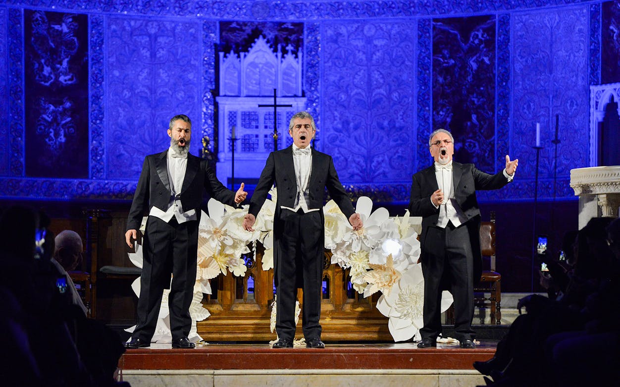 Opera singers performing on stage at a nighttime event with ornate blue backdrop.