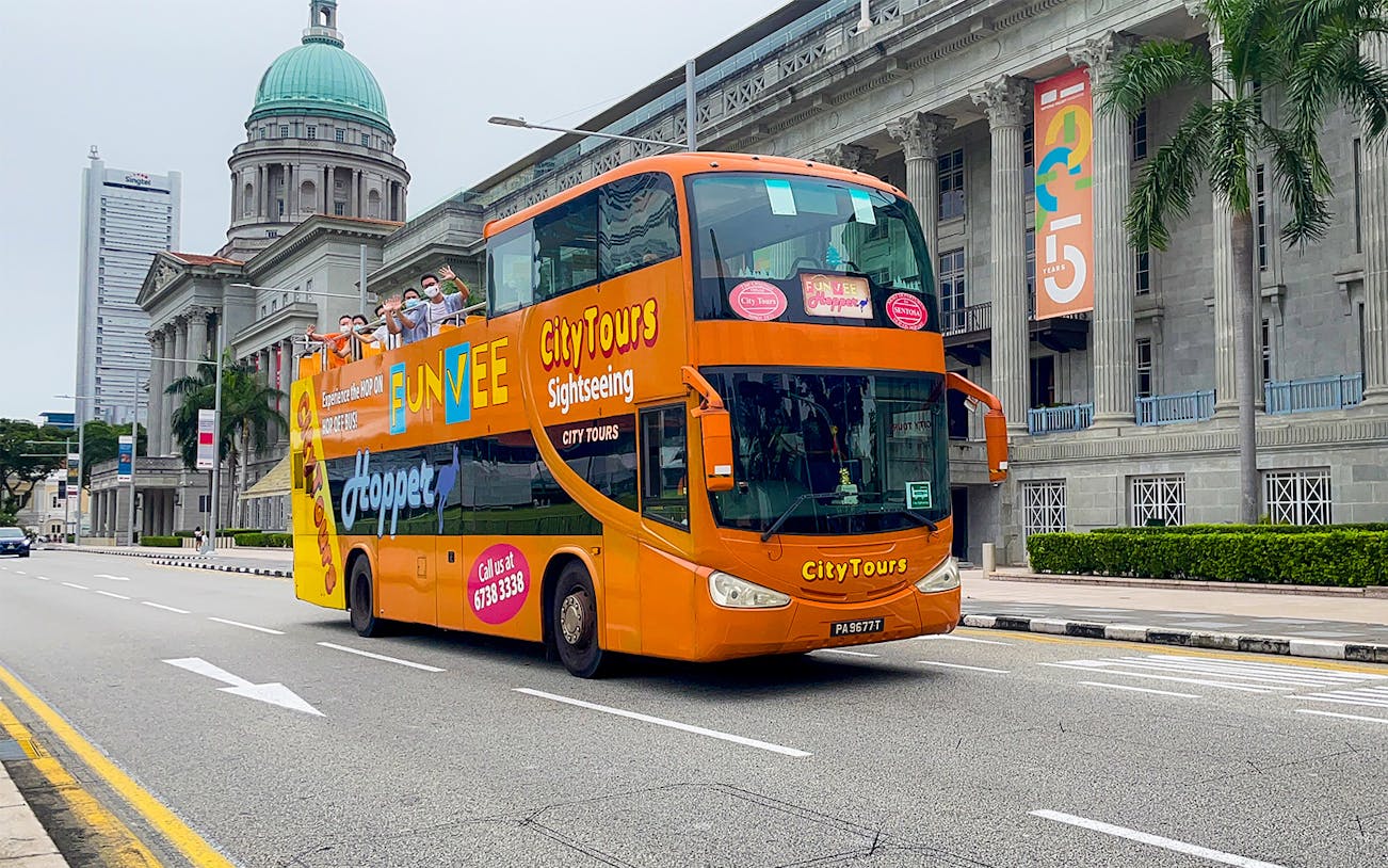 Open-top FunVee bus touring past historic buildings in Singapore.