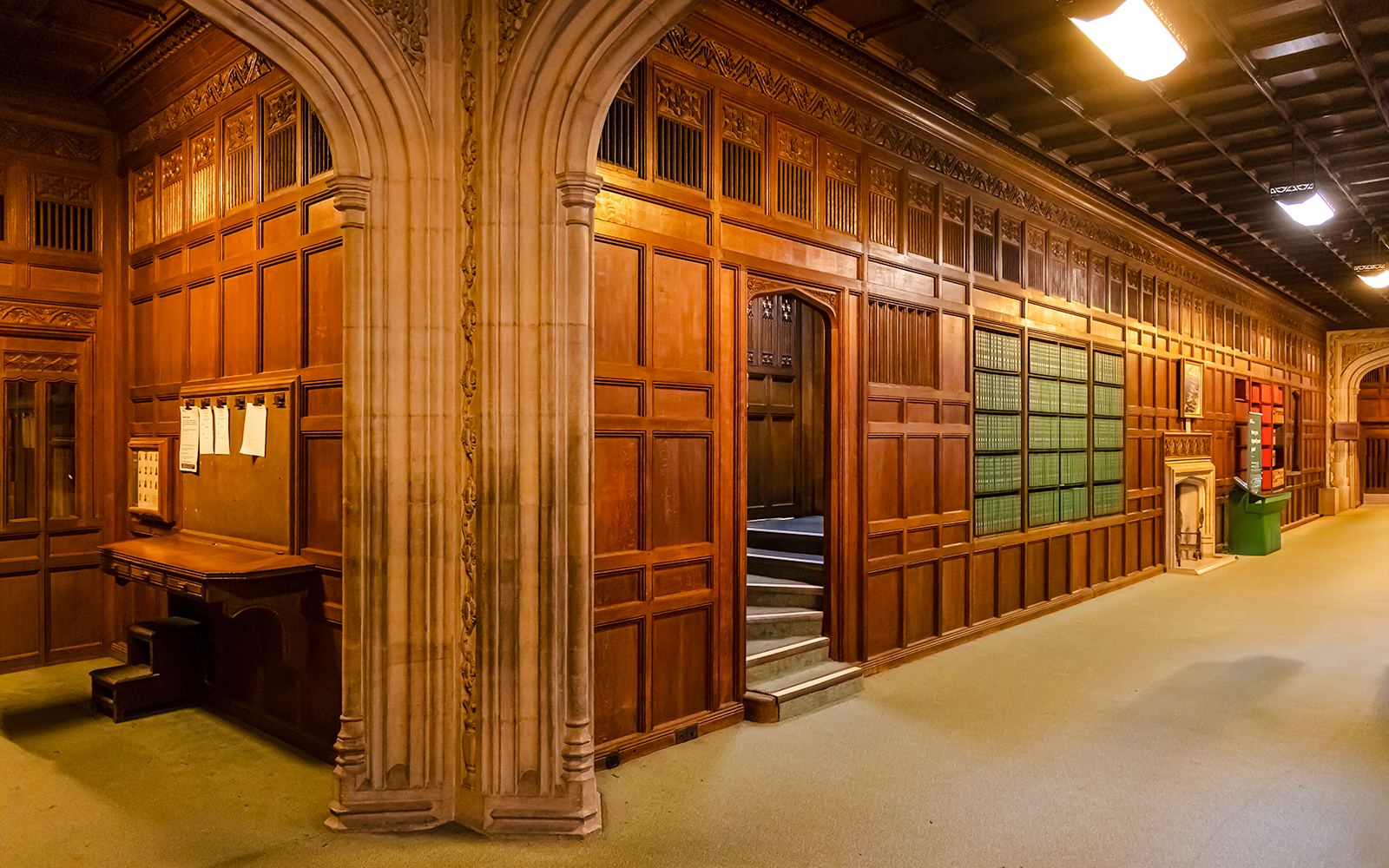 Members’ Lobby at Houses of Parliament with wooden paneling and archway.