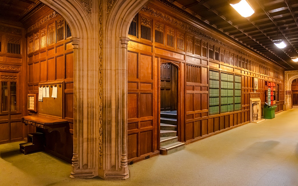 Members’ Lobby at Houses of Parliament with wooden paneling and archway.