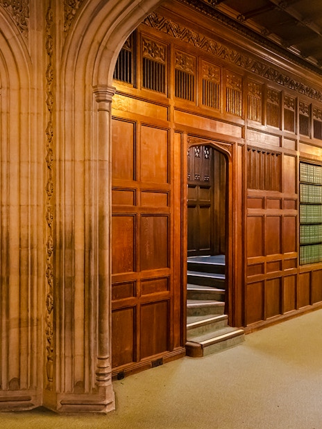 Members’ Lobby at Houses of Parliament with wooden paneling and archway.
